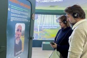 Two people read the FAQs on one of the plinths at the Missing Lynx Exhibition