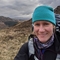 Dr Sam Cartwright standing in an upland lanscape beneath a dramatic sky