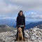 Carole standing atop a mountain, with her dog sat at her feet