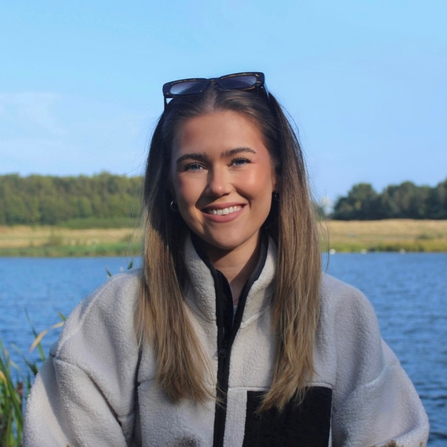 Laura Thompson, an ambassador for the Missing Lynx Project, standing in front of a lake