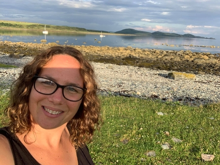 Lucy standing outside, with a rocky shore in the background