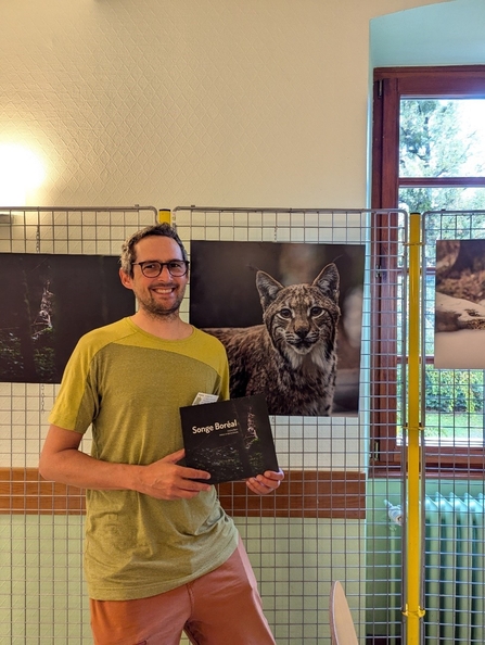 Photographer Antoine Rezer standing in front of some of his images of lynx