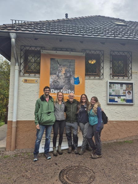 Five members of The Missing Lynx Project standing in front of a lynx poster