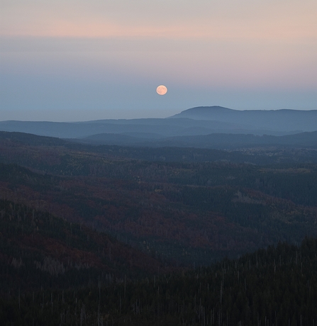 The hunter's moon over a landscape of trees and rolling hills